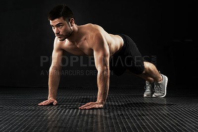 Buy stock photo Studio shot of a sporty young man doing push-ups isolated on black