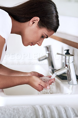 Buy stock photo Shot of a young woman washing her face in the bathroom at home