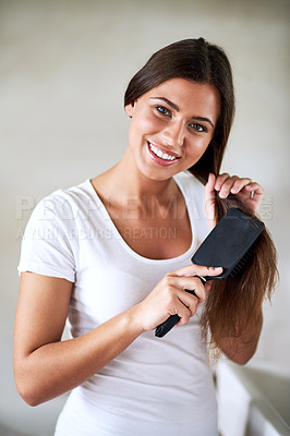 Buy stock photo Portrait of a beautiful young woman brushing her hair at home