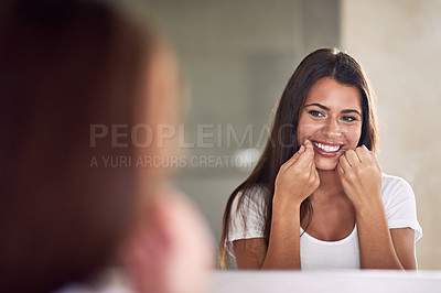 Buy stock photo Shot of a beautiful woman flossing her teeth while looking in the mirror