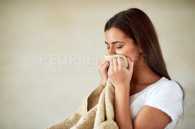 Buy stock photo Shot of young woman enjoying the smell of freshly washed towels