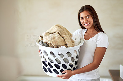 Buy stock photo Portrait of a happy young woman holding a full laundry basket