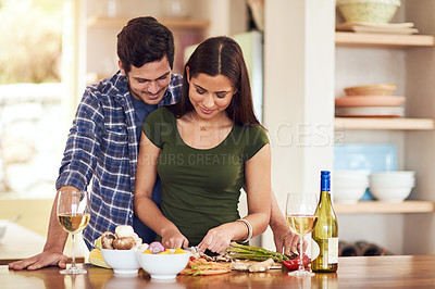 Buy stock photo Shot of a young couple preparing dinner together in their kitchen at home