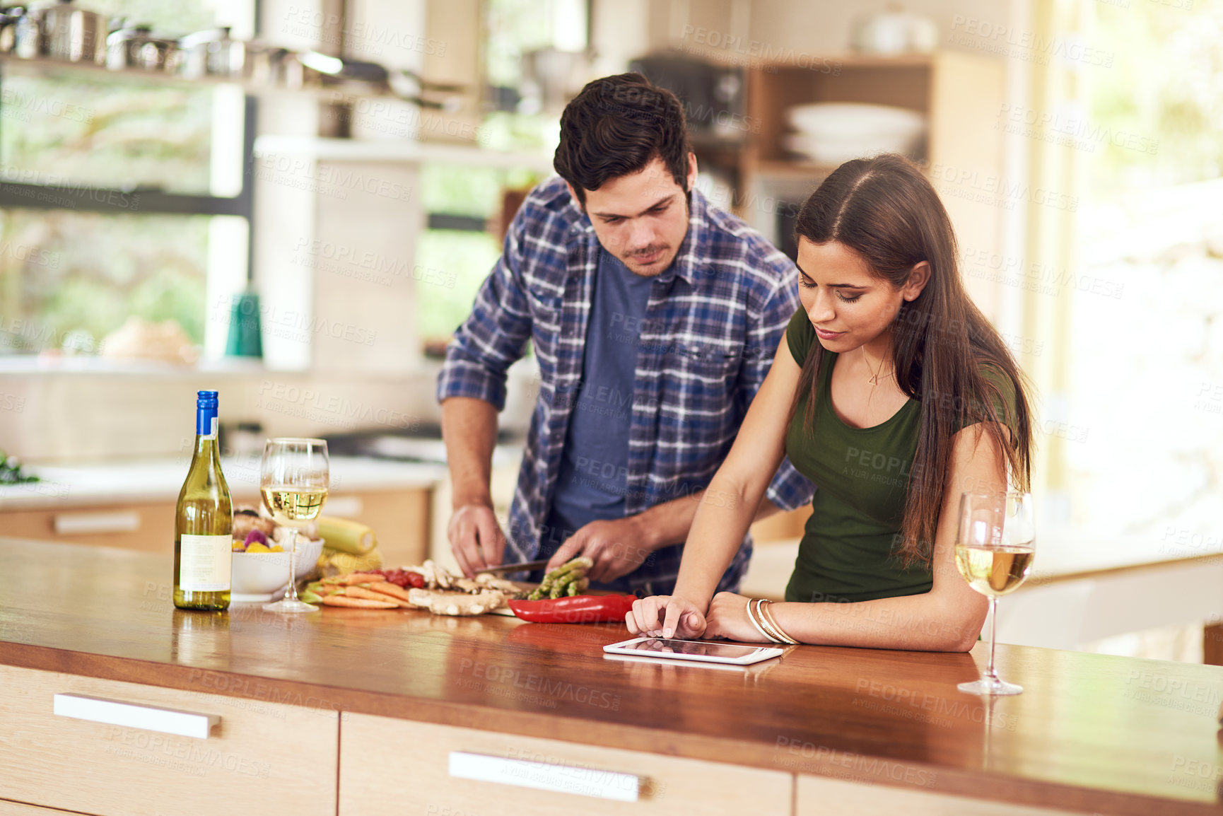 Buy stock photo Shot of a young couple preparing dinner together in their kitchen at home