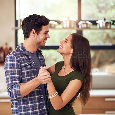 Buy stock photo Shot of a happy young couple dancing in their kitchen at home