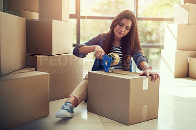Buy stock photo Shot of a young woman packing boxes while moving house