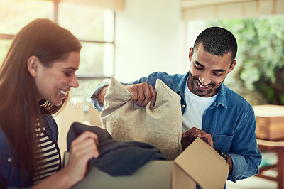 Buy stock photo Cropped shot of a young couple unpacking boxes while moving into their new home
