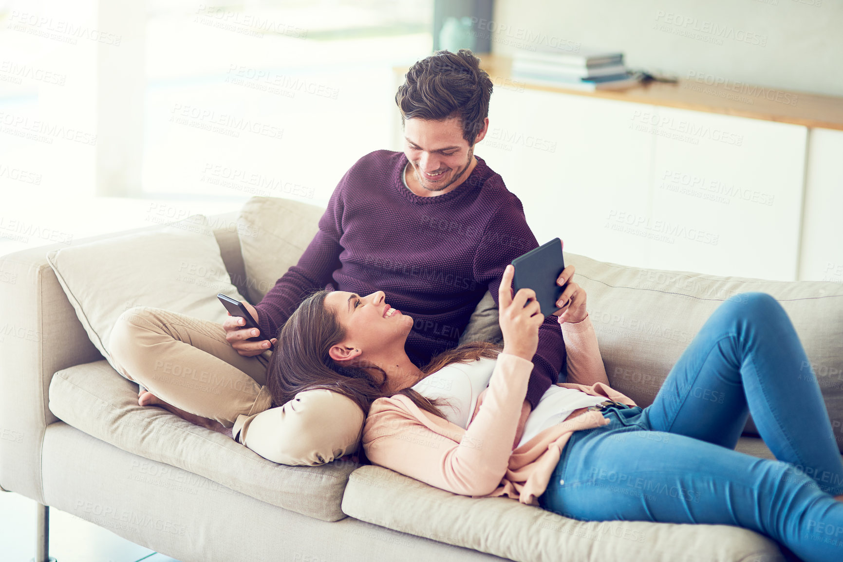 Buy stock photo Couple, talking and relax on sofa with tablet, phone and connectivity for app in home living room. Man, woman and technology with bonding, care and morning on vacation with smile on couch in house