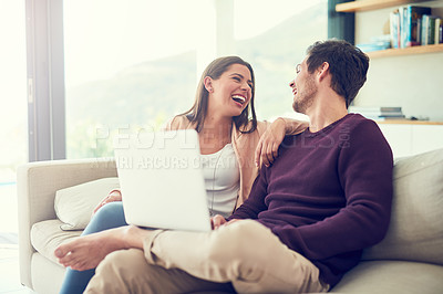Buy stock photo Shot of a smiling young couple using a laptop while relaxing on the sofa at home