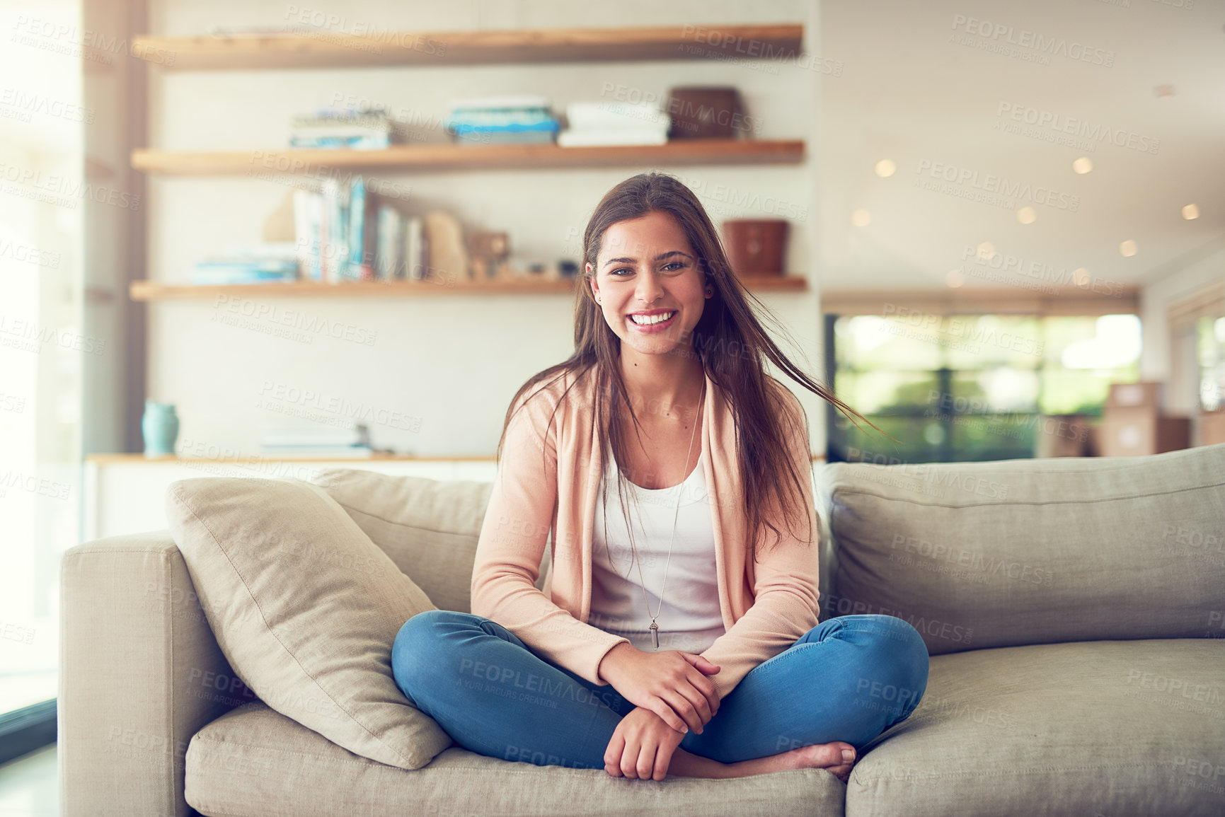 Buy stock photo Portrait of a smiling young woman relaxing on the sofa at home