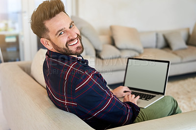 Buy stock photo Shot of a relaxed young man using a laptop on the sofa at home