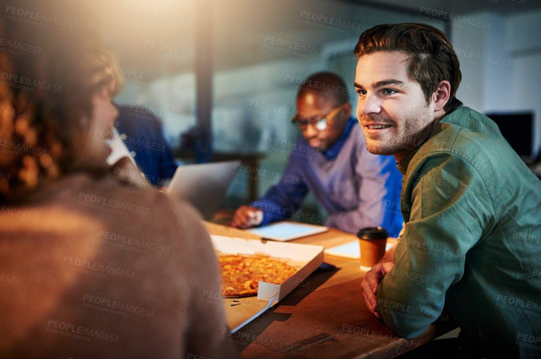 Buy stock photo Shot of a team of young businesspeople eating pizza while working late in the office