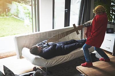 Buy stock photo Father, son and playing with sword in costume for cosplay, halloween or dress up at home. Little boy, child or playful kid with dad, crown and cardboard weapon for fun day or childhood in living room