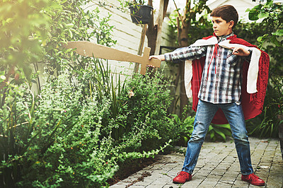 Buy stock photo Shot of a little boy in a cape playing outside with a cardboard sword