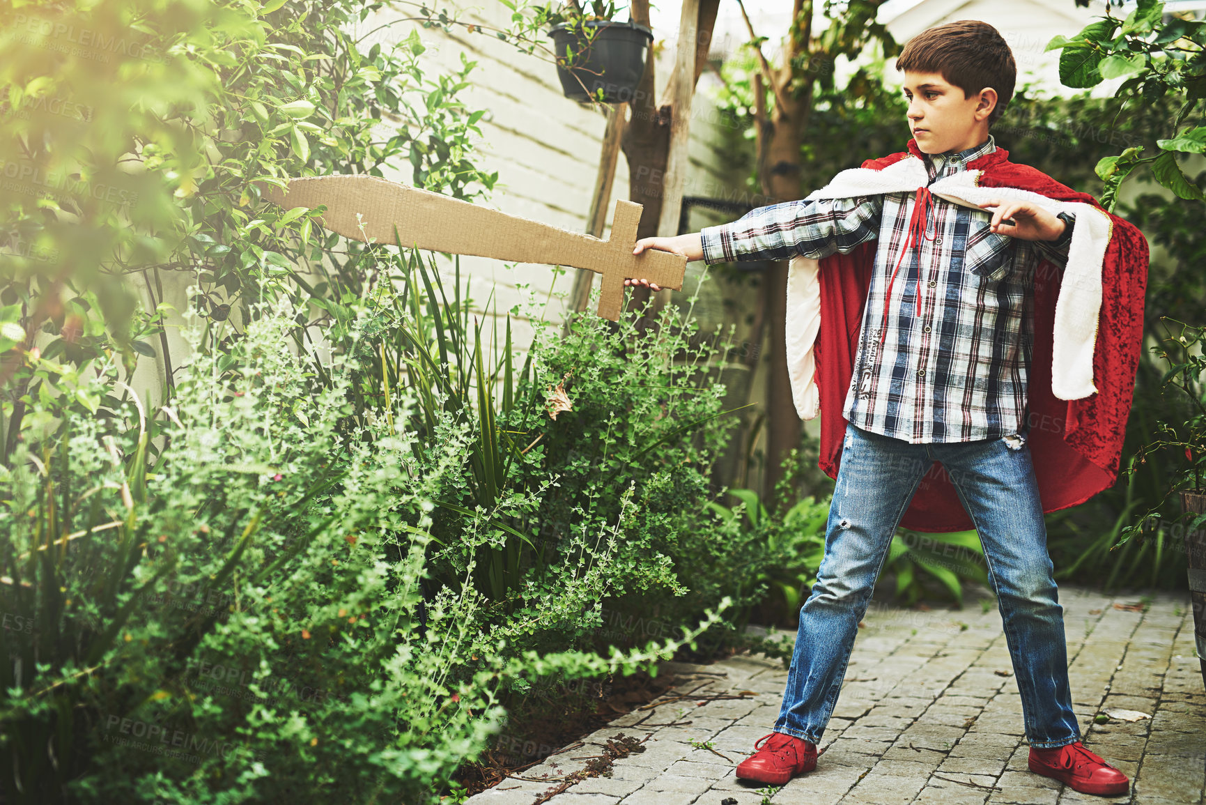 Buy stock photo Shot of a little boy in a cape playing outside with a cardboard sword