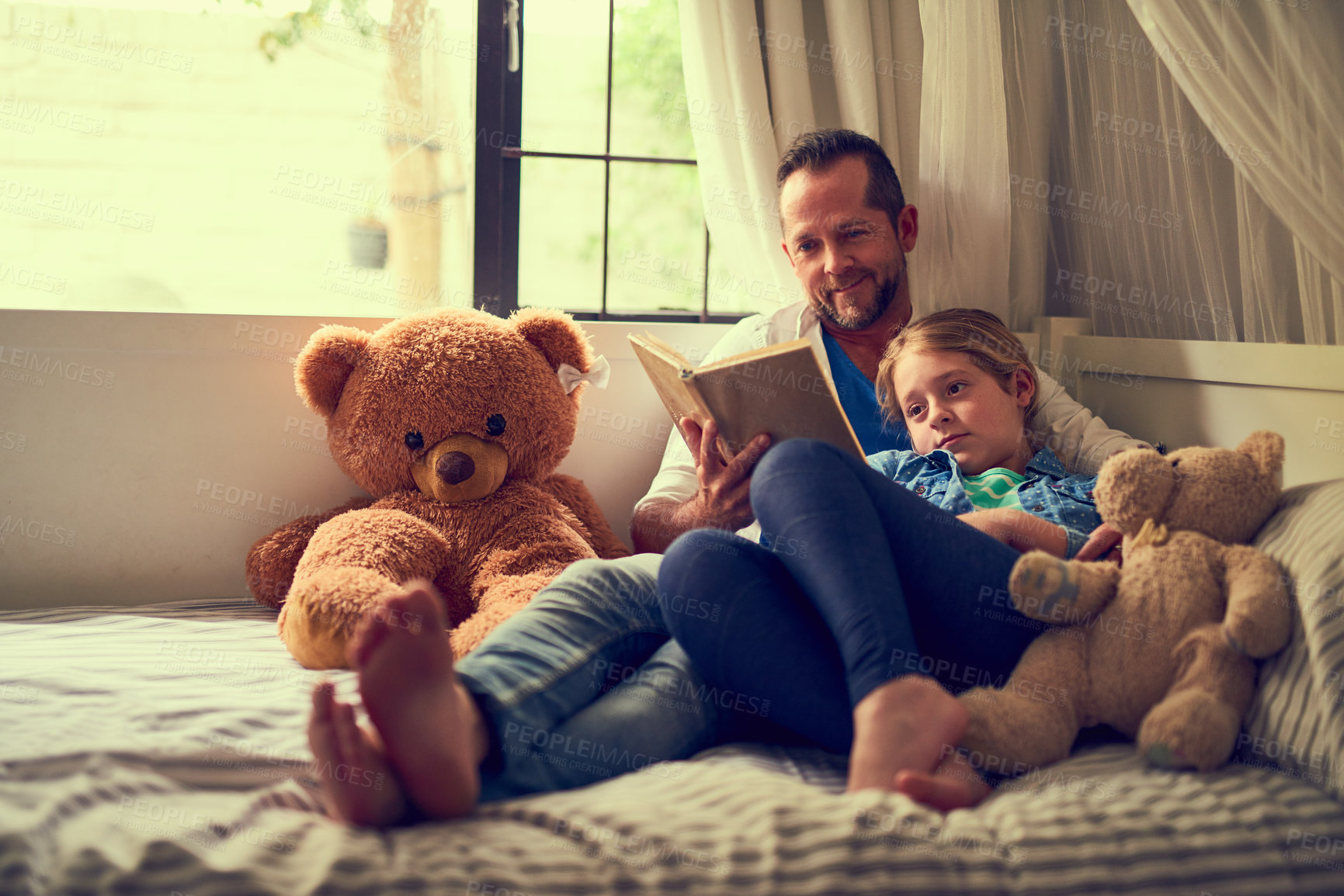 Buy stock photo Shot of a father reading a story to his little daughter at home