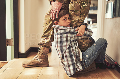 Buy stock photo Shot of a young boy clinging to his father's leg to stop him from going to the army