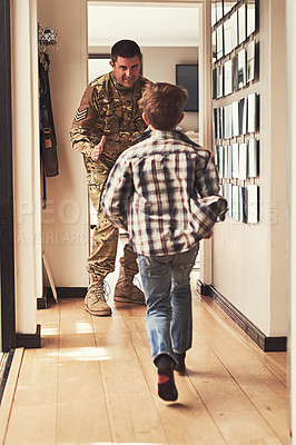 Buy stock photo Rearview shot of a little boy running to greet his father as he returns from the army