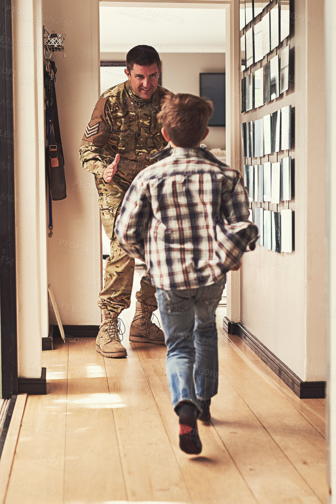 Buy stock photo Rearview shot of a little boy running to greet his father as he returns from the army