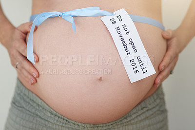 Buy stock photo Shot of an unidentifiable pregnant woman posing with a ribbon tied around her stomach