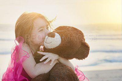 Buy stock photo Portrait of a cute little girl playing with her teddy bear on the beach