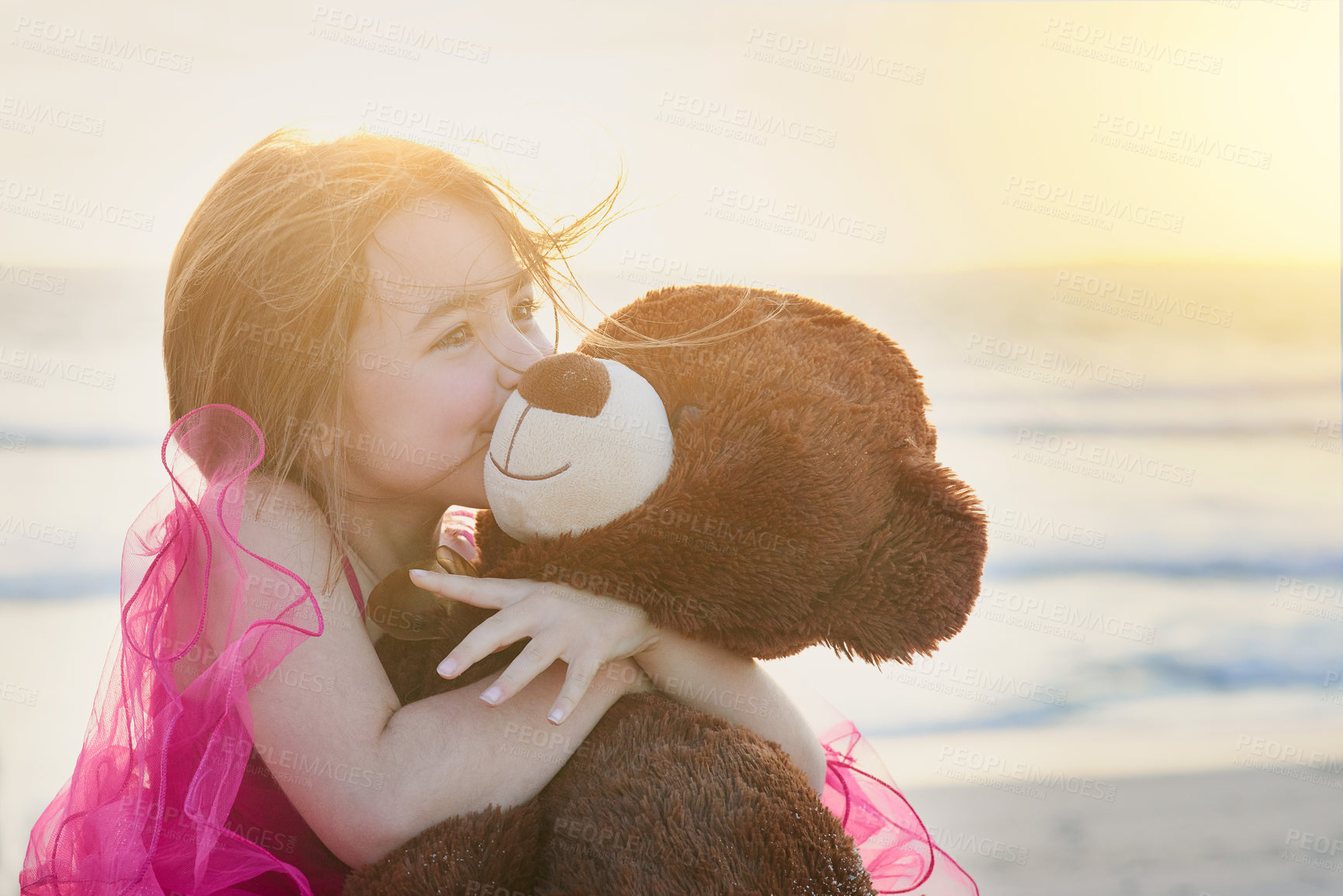 Buy stock photo Portrait of a cute little girl playing with her teddy bear on the beach