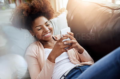 Buy stock photo Shot of a relaxed young woman using her phone on the sofa at home