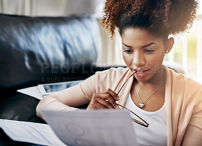 Buy stock photo Shot of a young woman going through her paperwork at home