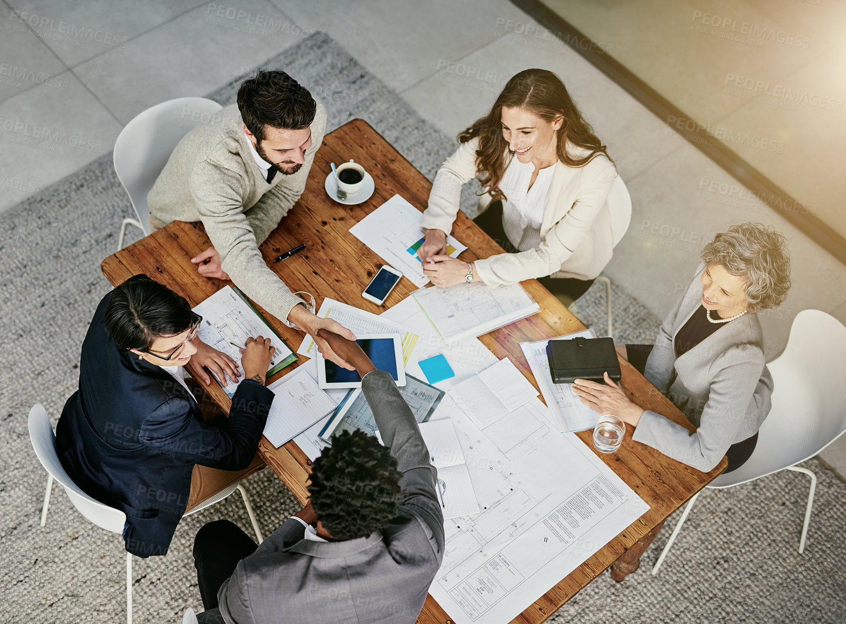 Buy stock photo Above, teamwork and handshake in workplace with documents for business deal, success and partnership. Collaboration, thank you and agreement for company, contract and leadership in conference room