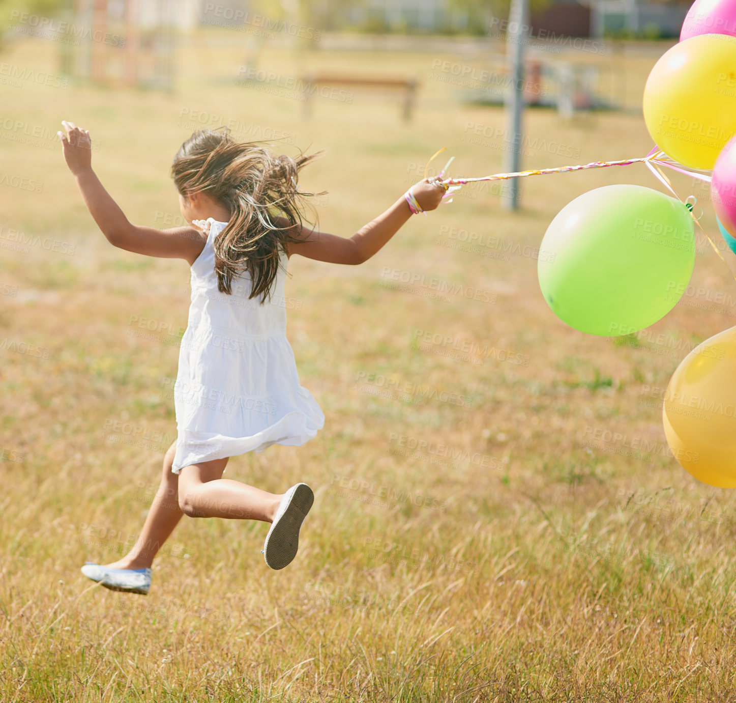 Buy stock photo Rear view shot of a little girl running through a field with a string of balloons outside