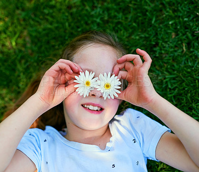 Buy stock photo Cropped shot of a little girl covering her eyes with flowers while playing outside