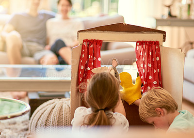 Buy stock photo Cropped shot of two siblings performing a puppet show for their parents at home