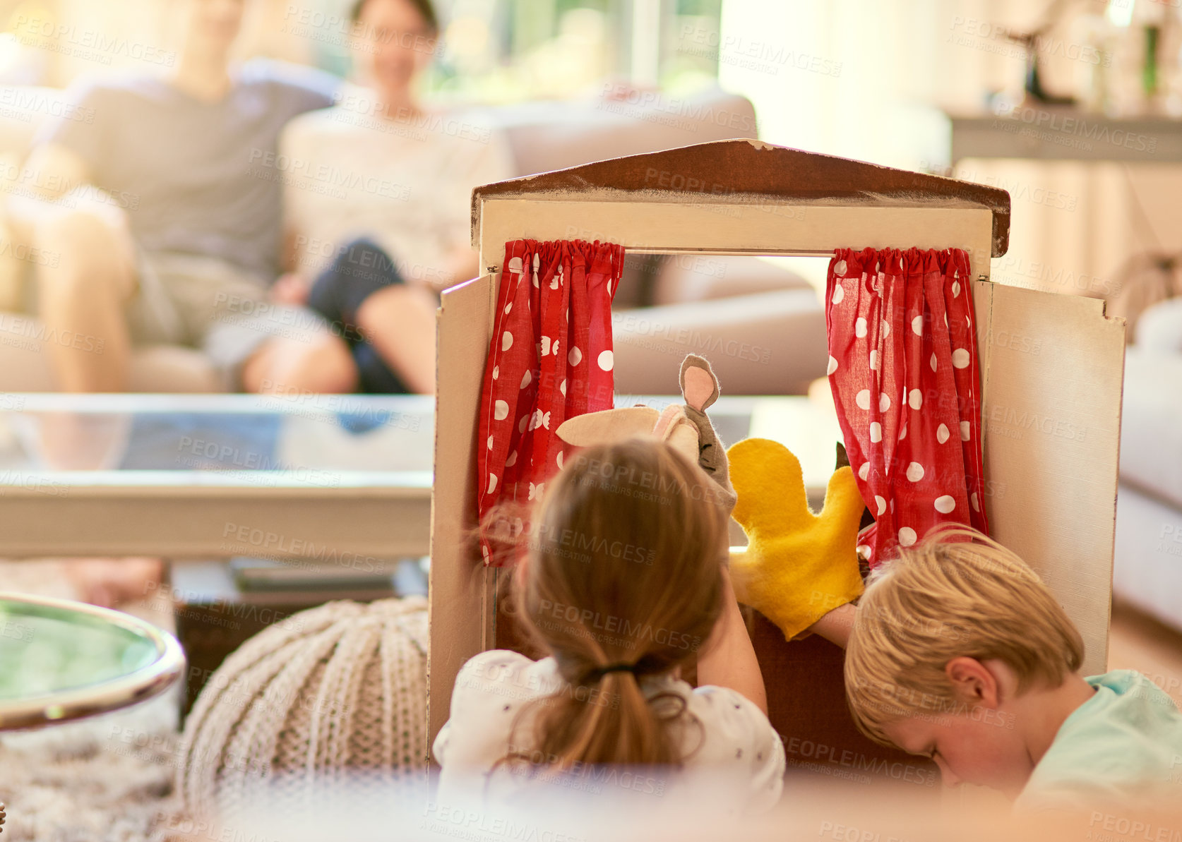 Buy stock photo Cropped shot of two siblings performing a puppet show for their parents at home