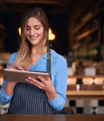 Buy stock photo Cropped shot of an attractive young woman using a digital tablet in her coffee shop