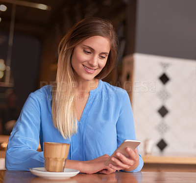 Buy stock photo Cropped shot of an attractive young woman using her cellphone in a coffee shop