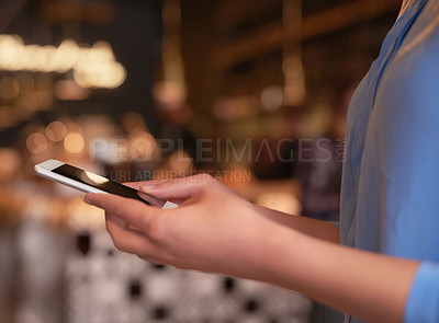 Buy stock photo Cropped shot of an unrecognizable woman using her cellphone in a coffee shop