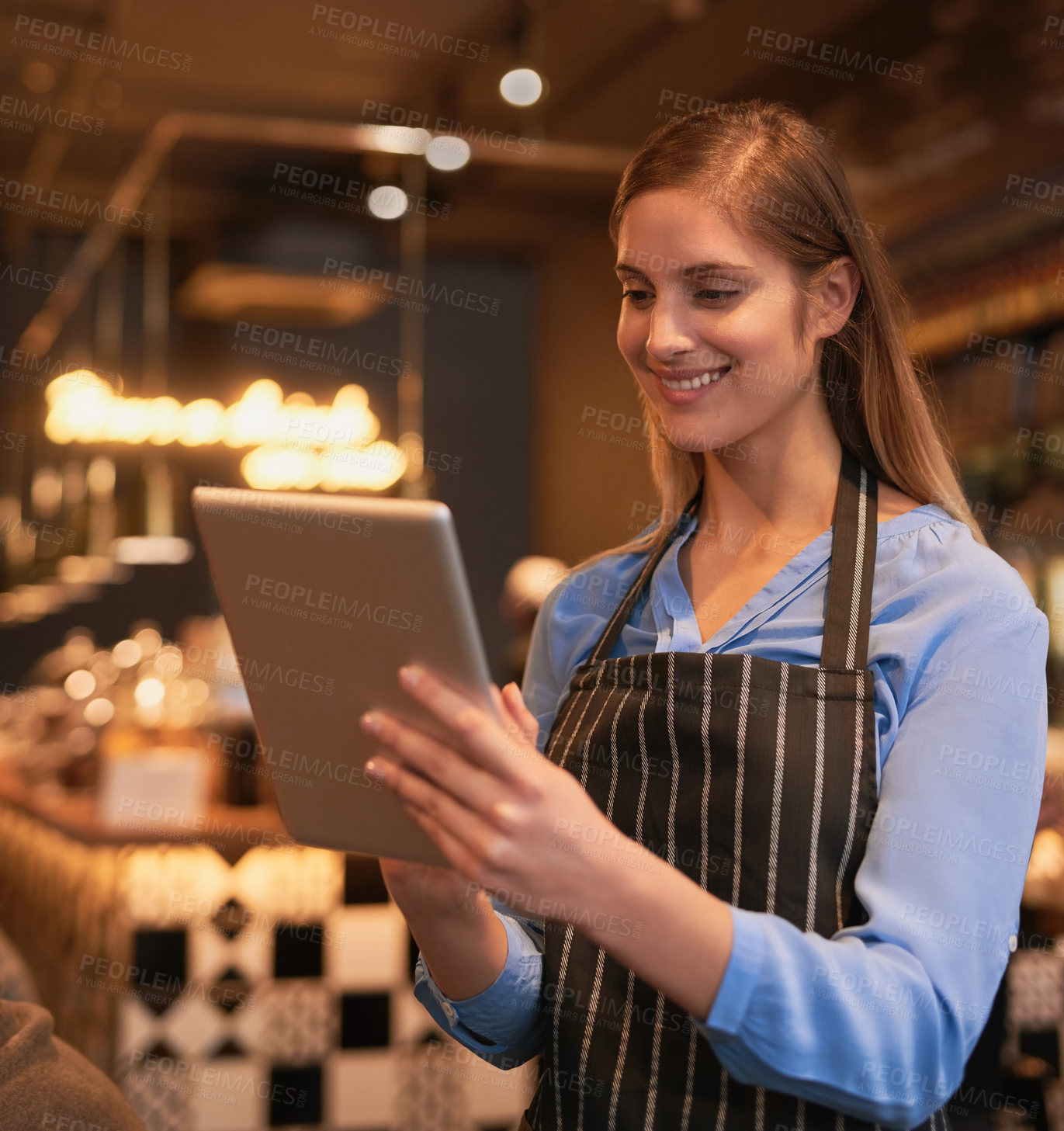 Buy stock photo Cropped shot of an attractive young woman using a digital tablet in her coffee shop