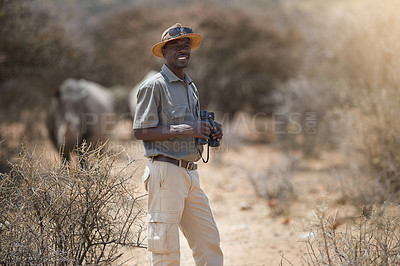 Buy stock photo Portrait of a confident game ranger looking at a group of rhinos in the veld