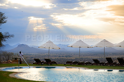 Buy stock photo Resort, pool and mountain with sunshine for vacation destination with clouds, blue sky and view. Worker, masseuse and sunlight with parasol for peaceful or zen for relaxing tranquil outdoor getaway.