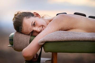 Buy stock photo Portrait, relax and massage with a woman lying in spa for wellness treatment at a luxury resort on vacation. Bed, zen or beauty and a female customer outdoor for stress relief with hot stone therapy