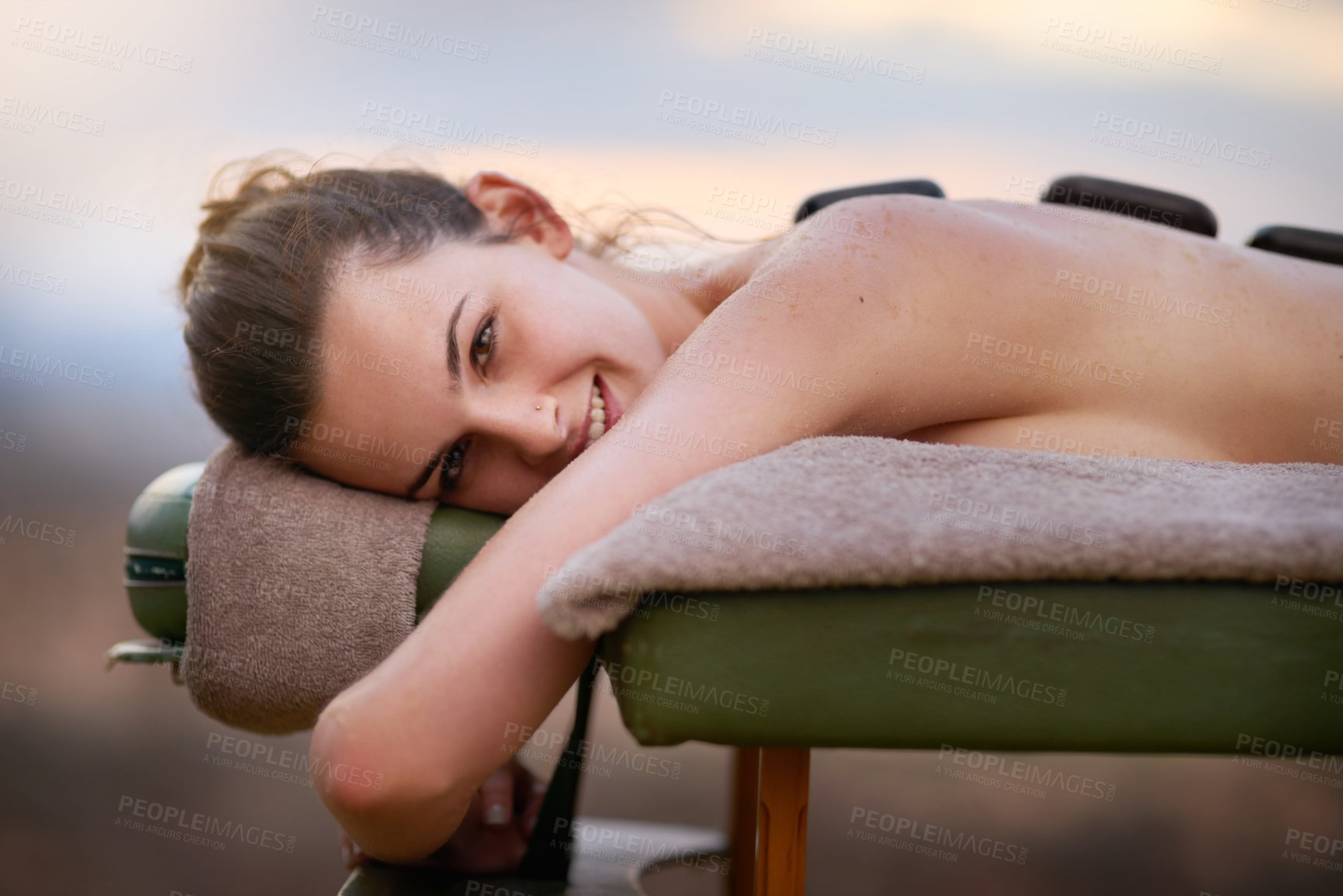 Buy stock photo Portrait, relax and massage with a woman lying in spa for wellness treatment at a luxury resort on vacation. Bed, zen or beauty and a female customer outdoor for stress relief with hot stone therapy