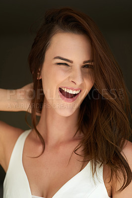 Buy stock photo Studio portrait of an attractive young woman winking against a black background