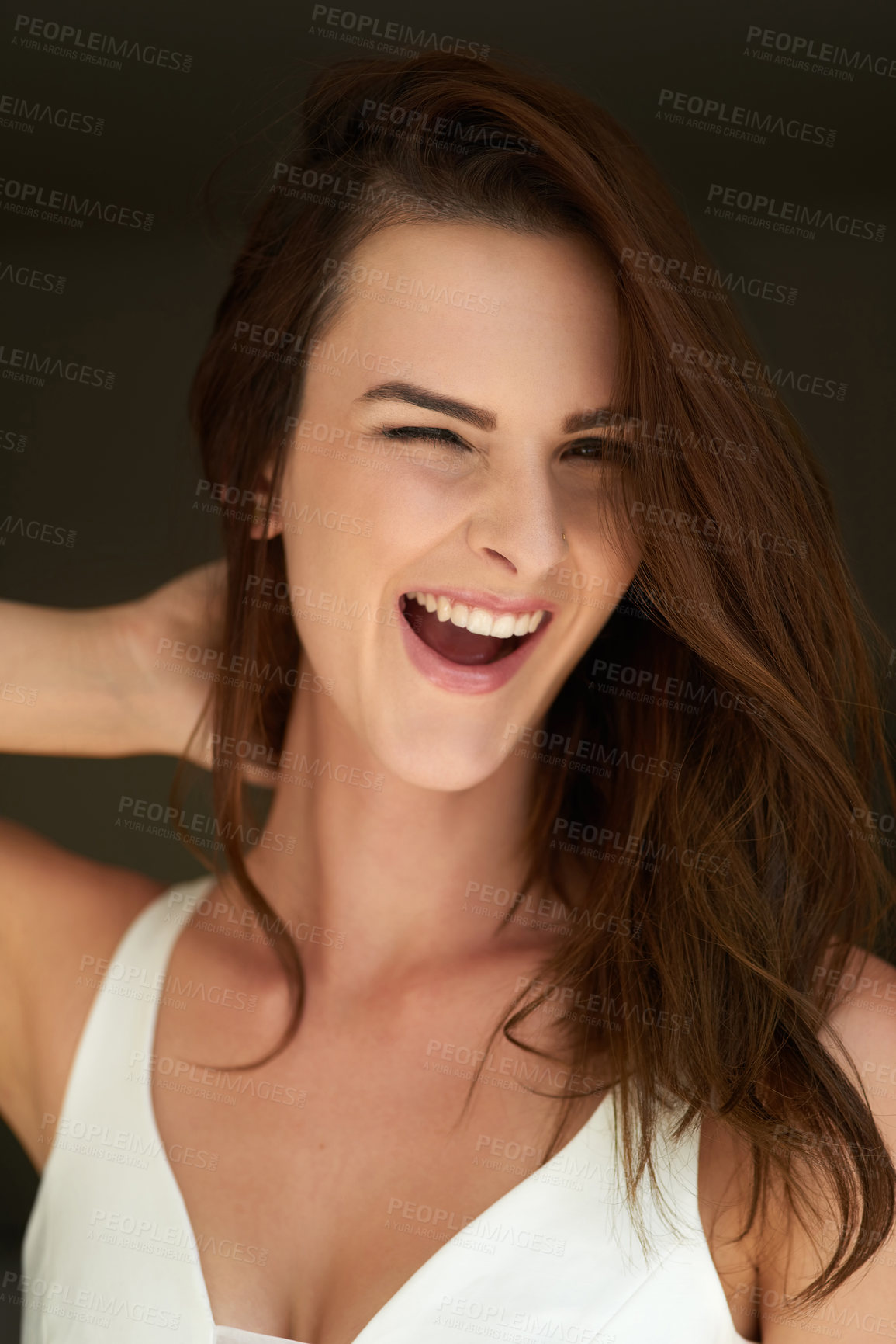 Buy stock photo Studio portrait of an attractive young woman winking against a black background