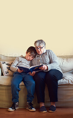 Buy stock photo Shot of a grandmother reading a book to her grandson at home