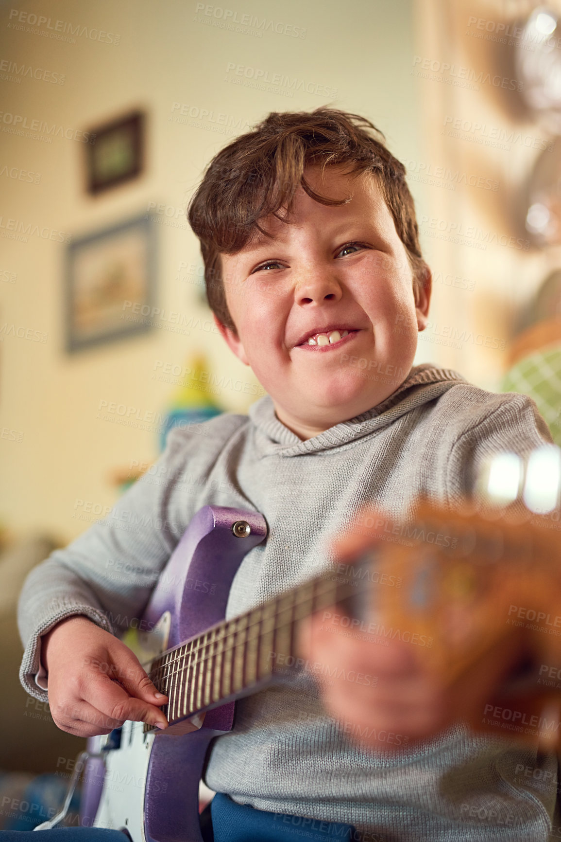 Buy stock photo Portrait of a little boy playing an electric guitar at home