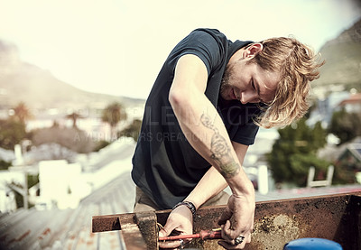 Buy stock photo Cropped shot of a handsome young man working outside on his roof