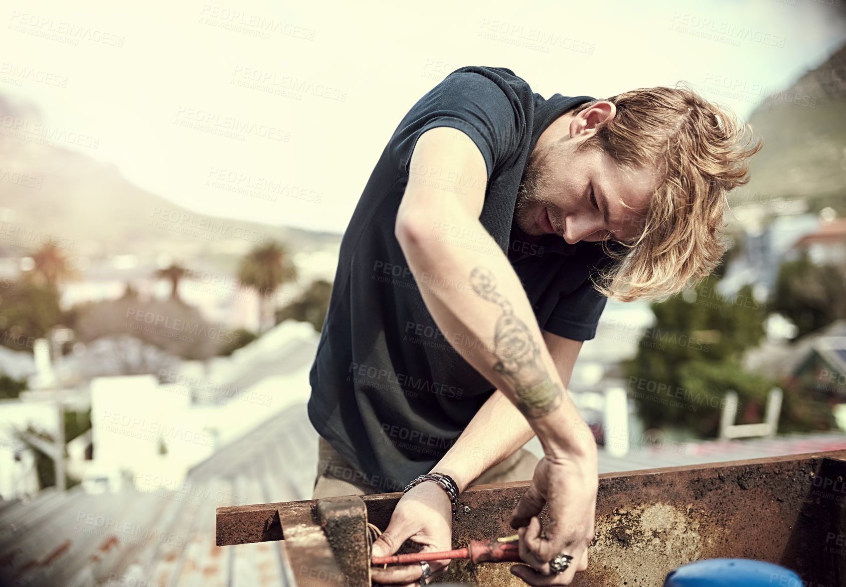 Buy stock photo Cropped shot of a handsome young man working outside on his roof