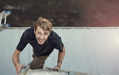 Buy stock photo High angle portrait of a handsome young man climbing a ladder outside