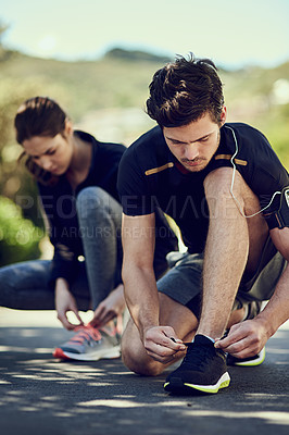 Buy stock photo Cropped shot of two young people tying their laces before a run