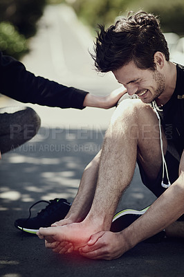 Buy stock photo Cropped shot of a young man suffering with foot cramp during a run